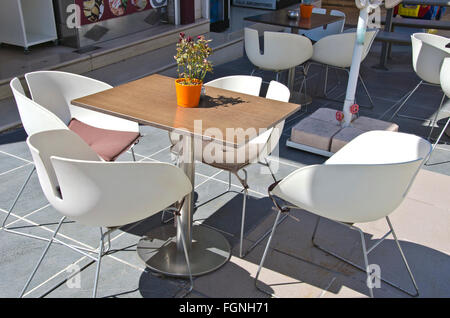 Tisch mit Stühlen mit eine verwelkte rose Pflanze in einem Topf im Café im Freien durch den Bürgersteig an sonnigen Tag Stockfoto