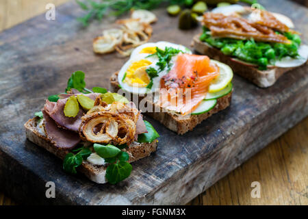 Skandinavische belegte Brötchen mit geräucherter Makrele, Lachs und Ei und Roastbeef und knusprigen Zwiebeln Stockfoto