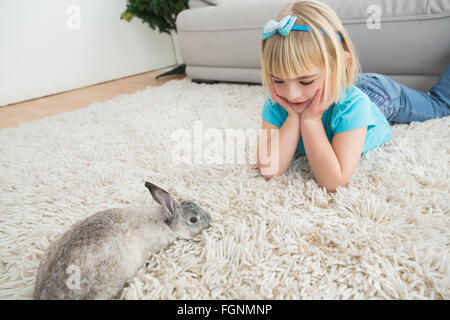 Kleines Mädchen auf Teppich liegend mit Kaninchen Stockfoto