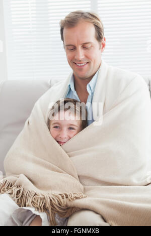 Vater und Sohn, eingewickelt in eine Decke auf der couch Stockfoto