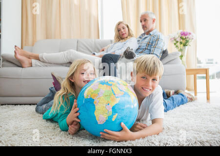 Geschwister, die Kugel auf dem Boden betrachten Stockfoto