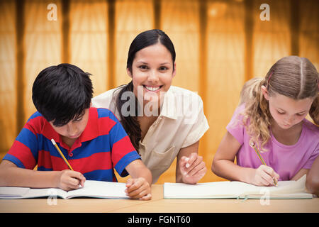 Zusammengesetztes Bild der hübschen Lehrerin helfen Schülern in Bibliothek Stockfoto