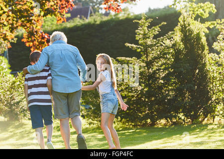 Porträt lächelndes Mädchen gehen mit Großmutter und Bruder im Garten Stockfoto