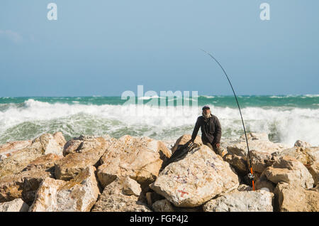 Fischer-Angler, bei rauer See, allein auf einer mediterranen Stein Pier Angeln Angeln. Spanien. Stockfoto