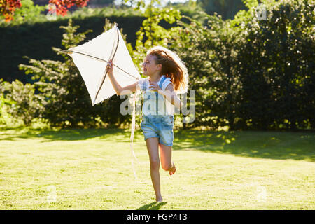 Mädchen mit Drachen im sonnigen Garten laufen Stockfoto