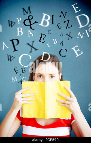 Zusammengesetztes Bild eines Schülers für Gesicht mit Buch in der Bibliothek Stockfoto