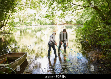 Vater und Sohn Fischen mit Netzen in Waldteich Stockfoto