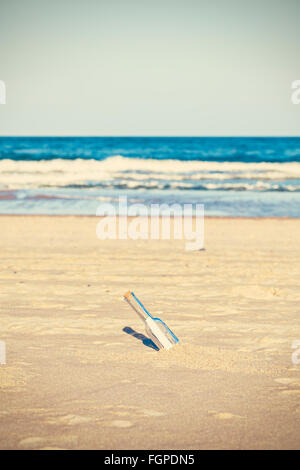 Gecrosst wird Foto einer Flasche mit Buchstaben am Strand, geringe Schärfentiefe. Stockfoto