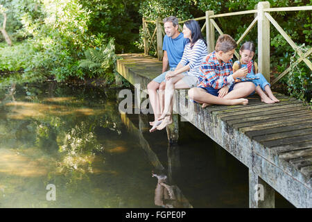 Familie entspannend auf Fußgängerbrücke über Teich Stockfoto