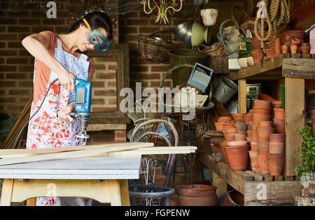 Frau mit macht Sander in Werkstatt Stockfoto