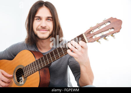 Attraktive glücklich junger Mann lächelnd und Holding Akustikgitarre auf weißem Hintergrund Stockfoto