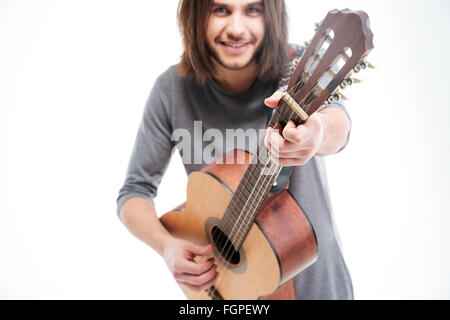 Attraktives Lächeln jungen Mann mit langen Haaren spielt akustische Gitarre auf weißem Hintergrund Stockfoto