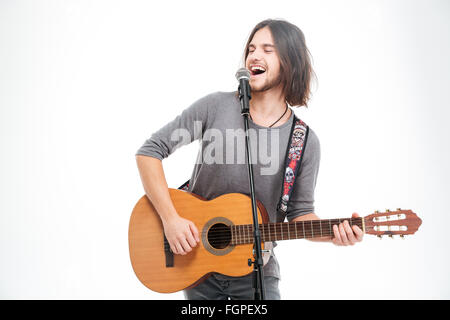Charismatische positive Jüngling in Mikrofon singen und Gitarre zu spielen, auf weißem Hintergrund Stockfoto