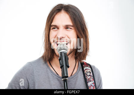 Nahaufnahme von attraktiven fröhlich junger Mann mit langen Haaren Gesang Mikrofon auf weißem Hintergrund Stockfoto