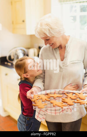 Enkelin umarmt Großmutter backen Lebkuchen Stockfoto
