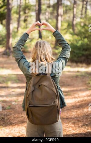 Rückansicht des blonden Wanderer Rahmung Herz mit Händen Stockfoto