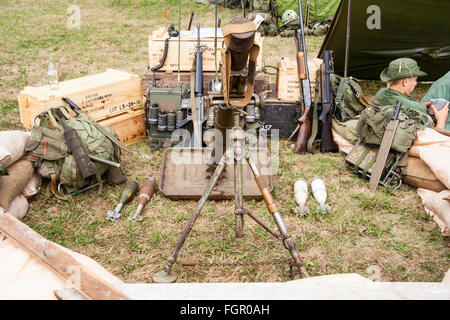 Vietnam Krieg Re-enactment. American heavy Mörtel in sandbagged Position mit verschiedenen Geräten an der Rückseite gegen Kisten gestapelt. Einige Soldaten entspannend. Stockfoto