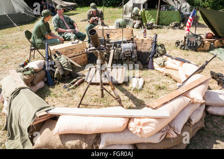 Vietnam Krieg Re-enactment. American heavy Mörtel in sandbagged Position mit verschiedenen Geräten an der Rückseite gegen Kisten gestapelt. Einige Soldaten entspannend. Stockfoto