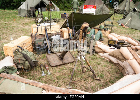 Vietnam Krieg Re-enactment. American heavy Mörtel in sandbagged Position mit verschiedenen Geräten an der Rückseite gegen Kisten gestapelt. Einige Soldaten entspannend. Stockfoto