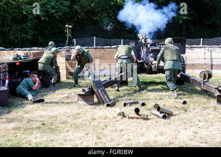 Vietnam Krieg Re-enactment. Ansicht der Rückseite zwei US 105 mm Haubitze Artilleriegeschützen neu bei Fire base beladen, während unter Beschuss. Marines in Deckung. Stockfoto