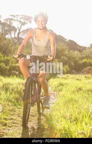 Lächelnde sportliche Brünette Mountainbiken Stockfoto