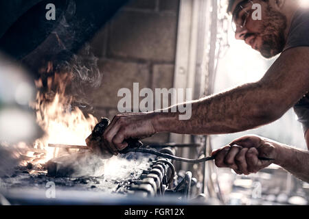 Schmied über Feuer in der Schmiede arbeiten Stockfoto