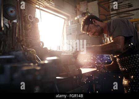 Schmied mit Sander in Schmiede Stockfoto