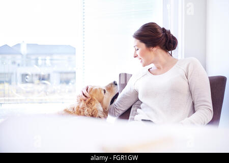 Frau Petting Hund am Fenster Stockfoto