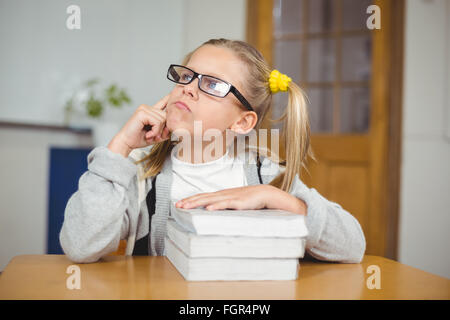 Nachdenklich niedlichen Schüler sitzt an ihrem Schreibtisch in einem Klassenzimmer Stockfoto