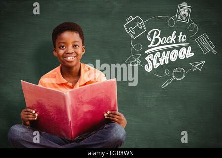 Zusammengesetztes Bild des netten jungen Lesebuch in Bibliothek Stockfoto