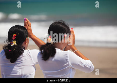 Seminyak, Bali Insel, Indonesien - 15. März 2015: zwei asiatische Frauen beten Händen am Ozean Strand bei Zeremonie Melasti vor Stille Tag Nyepi. Stockfoto