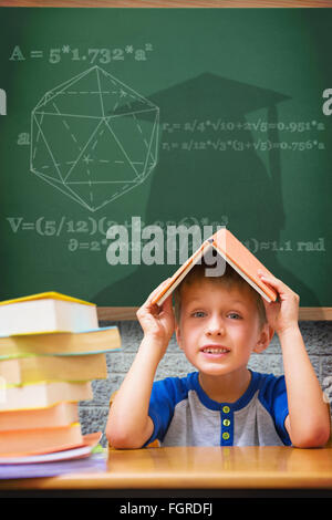 Zusammengesetztes Bild von netter Junge mit Buch auf Kopf Stockfoto