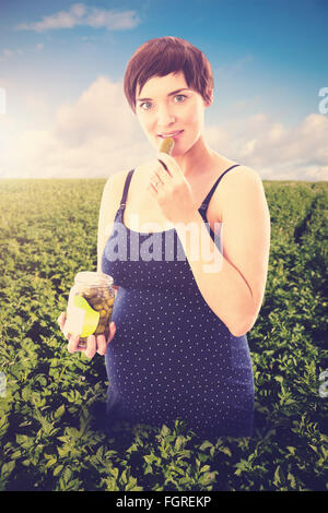 Zusammengesetztes Bild der schwangeren Frau Essen Glas Gewürzgurken Stockfoto