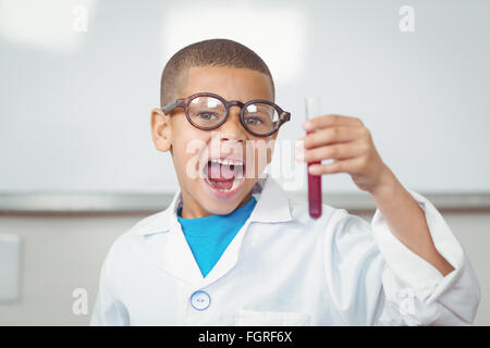 Überrascht Schüler mit Laborkittel Reagenzglas betrachten Stockfoto