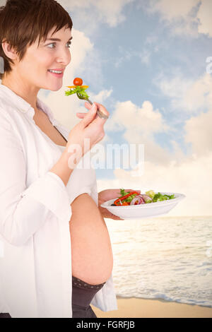 Zusammengesetztes Bild des lächelnden schwangere Frau mit Salat Stockfoto