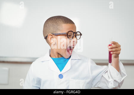 Überrascht Schüler mit Laborkittel Reagenzglas betrachten Stockfoto