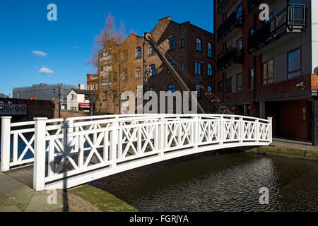 Eine Fußgängerbrücke und Kran im Paradies Wharf am Ashton Kanal in der Nähe von Stadtzentrum am Piccadilly, Manchester, England, UK Stockfoto