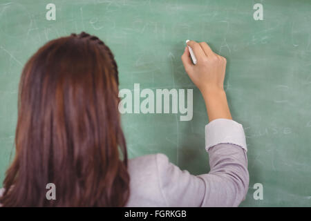 Rückansicht der Lehrer schreibt an die Tafel im Klassenzimmer Stockfoto