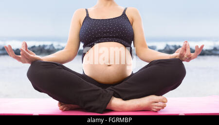 Zusammengesetztes Bild der schwangeren Frau sitzt auf Matten in Lotus-pose Stockfoto