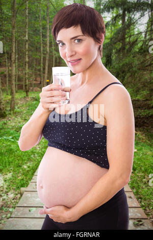 Zusammengesetztes Bild der schwangeren Frau Glas Wasser trinken Stockfoto