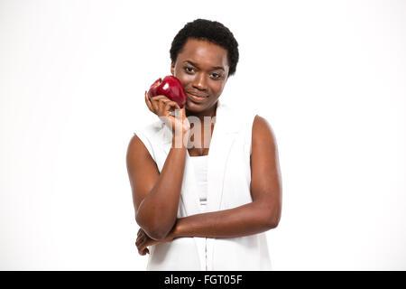 Schöne lächelnd afroamerikanische junge Frau stehen und hält roten Apfel auf weißem Hintergrund Stockfoto