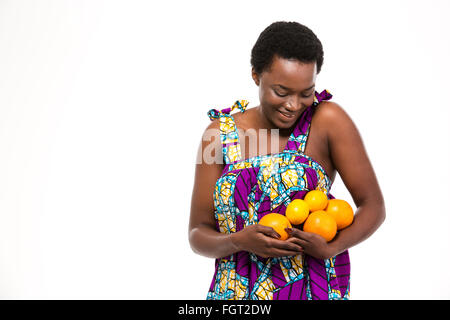 Ziemlich zufrieden afroamerikanischen jungen Frau in hellen Sommerkleid mit Orangen und Zitronen auf weißem Hintergrund Stockfoto