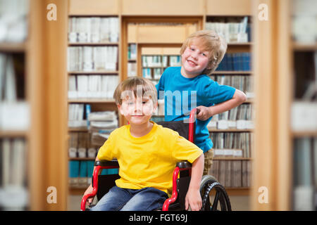 Zusammengesetztes Bild fröhlicher Junge Freund im Rollstuhl schieben Stockfoto