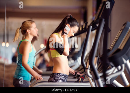 Zwei passen Frauen laufen auf Laufbändern im modernen Fitnessraum Stockfoto