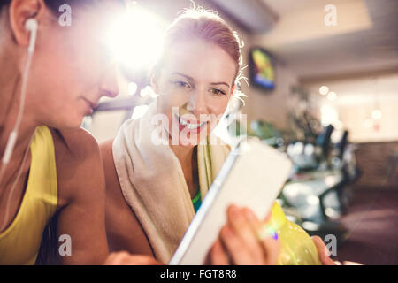 Passen zwei attraktive Frauen im Fitness-Studio mit Smartphone Stockfoto