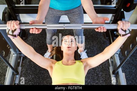 Frau mit Personaltrainer Bank drücken mit Gewichten, Fitness-Studio Stockfoto