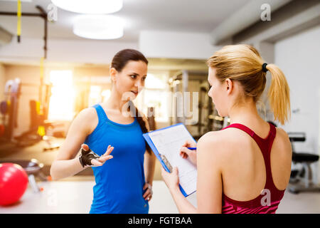 Frau im Fitness-Studio, Personaltrainer, Consultiing Plan in Zwischenablage Stockfoto