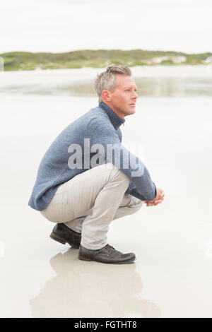 Mann kauerte am Ufer Stockfoto