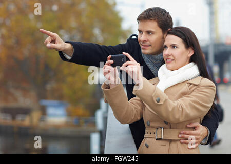 Paar auf Städtereise fotografieren mit Handy Stockfoto