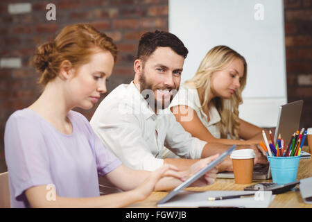 Porträt von lächelnden Mann sitzt inmitten von Kollegen Stockfoto